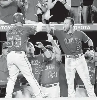  ?? Harry How Getty Images ?? KOLE CALHOUN IS GREETED in the dugout by Taylor Feathersto­n (8) and others after scoring the go-ahead run in the bottom of the eighth inning on Albert Pujols’ single.