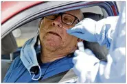  ?? Miami. AP ?? Carlos Garcia leans back as a medical profession­al inserts a swab into his nose to collect a sample to test for COVID-19 at a drive-through testing site Friday in