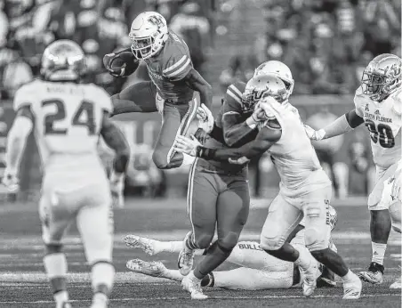  ?? Michael Ciaglo / Staff photograph­er ?? Houston’s D'Eriq King (4) hurdles South Florida’s Mazzi Wilkins (23) during the second half Saturday at TDECU Stadium. King accounted for seven touchdowns.