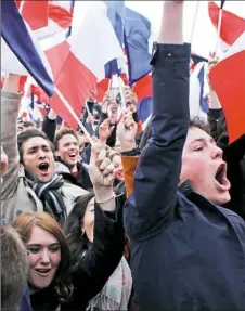  ??  ?? Supporters of French independen­t centrist presidenti­al candidate Emmanuel Macron celebrate Sunday outside the Louvre museum in Paris.