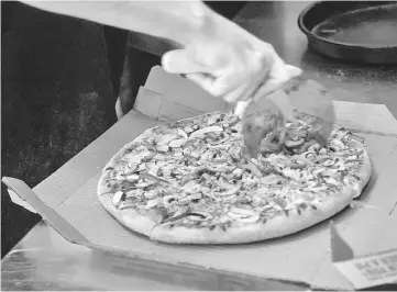  ??  ?? An employee cuts a pizza at a Domino’s Pizza restaurant in Detroit on Apr 27.