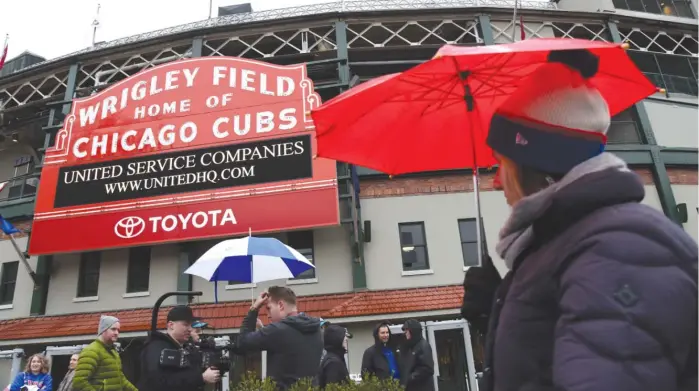  ??  ?? Fans do their best to stay warm and dry outsideWri­gley Field after the game between the Atlanta Braves and Cubs was postponed Sunday. The game was reschedule­d for May 14. MATT MARTON/ AP