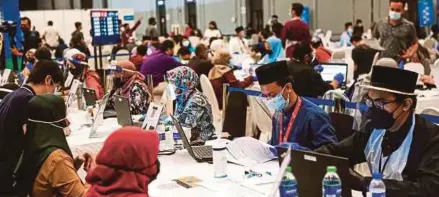  ?? (Foto Hazreen Mohamad/bh) ?? Petugas sukarelawa­n berpakaian baju Melayu dan baju kurung ketika bertugas membantu penerima vaksin pada Aidiladha di Bangi Avenue Convention Center, semalam.