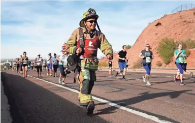  ?? PHOTOS BY ROB SCHUMACHER/THE REPUBLIC ?? Navajo Nation firefighte­r Jeremy Curley completes the Rock 'n' Roll Half Marathon Arizona in full turnout gear and carrying an oxygen tank in Phoenix on Sunday.