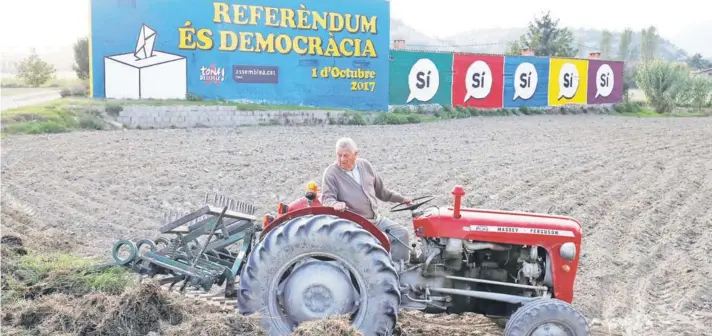  ??  ?? ► Un agricultor de la localidad de Tona, en la provincia de Barcelona, conduce ayer un tractor con un mensaje pro-independen­cia de fondo.