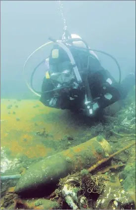  ?? — Photo by Jeffrey Gallant, Geerg.ca/special to The Telegram ?? Jean-Robert Bourgeois examines an unexploded gun shell from the wreck of the HMS Raleigh near L’Anse Amour, Labrador.