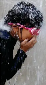  ??  ?? A young girl cools down from the searing heat in a fountain in central Tokyo