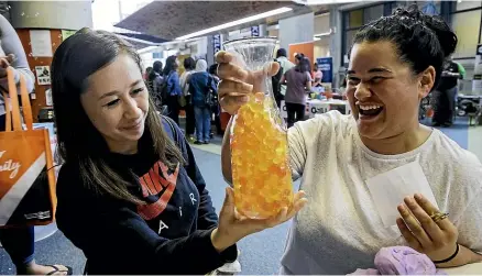  ?? DAVID UNWIN/STUFF ?? Laquesha Mccarthy, left, and Chelsea Mumby try to guess how many balls are in the beaker at UCOL’S orientatio­n week.