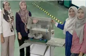  ??  ?? Intan Mastura Saadon (dua dari kiri) dengan mesin pemotong ikan automatik yang dihasilkan bersama barisan penyelidik UTEM.