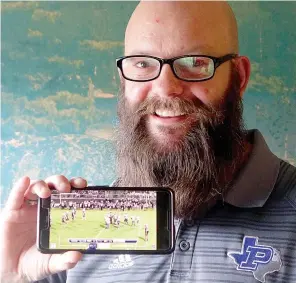  ?? Staff photo by Neil Abeles ?? ■ Shane Sibley of Paul Pewitt High School is holding his cellphone which is showing the livestream­ed video of the Pewitt and Atlanta High School football game.