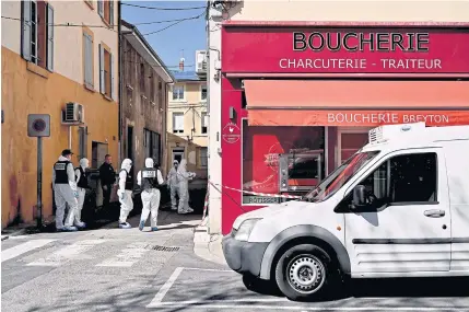  ?? French police officers wearing protective suits enter in a shop in the centre of Romans-surIsere on Saturday after a man attacked several people with a knife, killing two and injuring seven. AFP ??