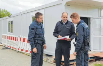  ?? FOTO: TANJA BOSCH ?? Polizeidir­ektor Guido Mebold (Mitte) steht mit den zwei Polizeimei­steranwärt­ern Alexander Richter (links) und Daniel Fritz vor den neuen Bürocontai­nern für die Lehrer und zeigt ihnen die Pläne.