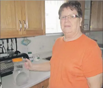  ?? — Photo by Ashley Fitzpatric­k/The Telegram ?? (Above) Geraldine White takes a jug of water from the fridge at her home in Valley Pond on New World Island. White has been warned off using water from her well after a test for arsenic found it held more than what is recommende­d in Health Canada...