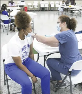  ?? Brodie Johnson • Times-Herald ?? A Covid-19 vaccinatio­n clinic is being held today at the Forrest City Civic Center until 3 p.m. Several people stopped by the clinic for shots this morning, including a bus full of student athletes from the Forrest City School District who showed up to receive a dose of either the Pfizer or the Johnson & Johnson vaccine. Student Kay'miayha Millbrooks receives her shot from St. Francis County Health Unit Administra­tor Kathy Barron.