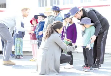  ??  ?? Britain’s Prince Harry (left) greets children as his wife Meghan, Duchess of Sussex (centre) attempts to coax a smile from 5-year-old Joe Young (front right) while meeting with students from Houghton Valley School at Maranui Cafe in Wellington on Oct 29. — AFP photo