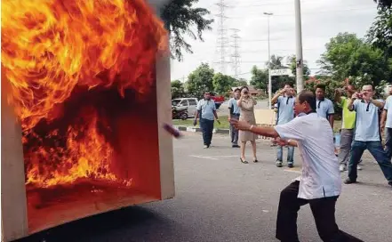  ??  ?? Checking it out: Chor throwing a bottle of SAT119 into a fire during a demonstrat­ion at the product launch in Malacca yesterday.