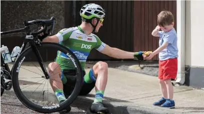  ?? MORGAN TREACY/INPHO ?? Przemyslaw Kasperkiew­icz of the Ireland An Post Chain Reaction team gives his energy bar to a three-year-old David Murray from Dungloe at the start of yesterday’s Stage 6 of the Rás