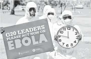  ?? — AFP photo ?? Protesters carry clocks to show time is running out during an Ebola protest event in Brisbane.