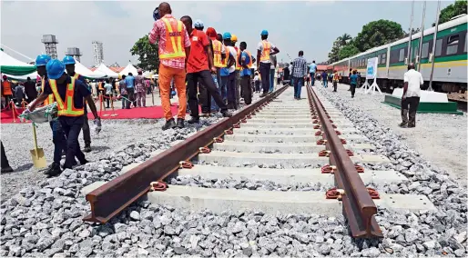  ??  ?? Workers stand along a prototype rail line during the ground breaking for the constructi­on of Lagos-Ibadan rail line in Lagos on March 7, 2017.