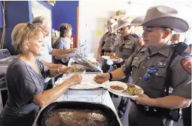  ?? Gabe Hernandez / Corpus Christi Caller-Times via AP ?? Aspring break dinner break Brenda Porter helps serve meals to DPS troopers Monday in Port Aransas. First responders and their families receive a free dinner at the Port Aransas Police Department every day of spring break before they resume their patrol...