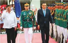  ?? Reuters ?? Philippine President Duterte salutes with Chinese Premier Li Keqiang as they review honour guards during Li ’s official visit at the presidenti­al palace in Manila yesterday.