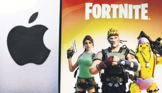  ??  ?? The Fortnite game graphic is displayed on a smartphone in front of the Apple logo in this illustrati­on taken May 2, 2021.