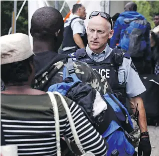  ?? THE CANADIAN PRESS/THE ASSOCIATED PRESS/FILES ?? An RCMP officer standing in Saint-Bernard-de-Lacolle, Que., advises migrants that they are about to illegally cross from New York state, and will be arrested.