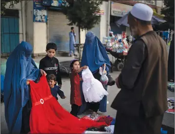  ?? (AP/Felipe Dana) ?? Afghan women and a girl shop for dresses Sept. 10 at a local market in Kabul.