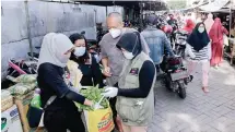  ?? ALFIAN RIZAL/JAWA POS ?? HARI PEDULI SAMPAH NASIONAL: Relawan penggiat lingkungan mengganti tas kresek yang dibawa pengunjung Pasar Karah dengan tas kain.