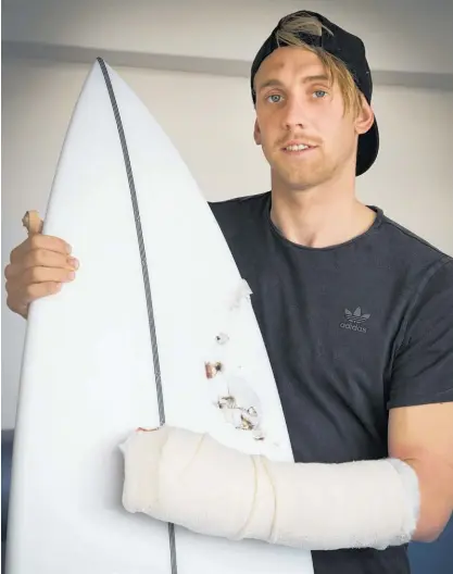  ?? Photo / Brett Phibbs ?? Andrew Brough shows his new surfboard — complete with a great white’s tooth embedded.