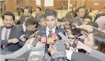  ??  ?? Syed Saddiq (centre) talks to reporters at the Parliament Lobby. — Bernama photo