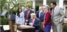  ?? EVAN VUCCI AP ?? President Donald Trump signs an executive order creating the White House Hispanic Prosperity Initiative on July 9. Trump and others present did not wear masks.