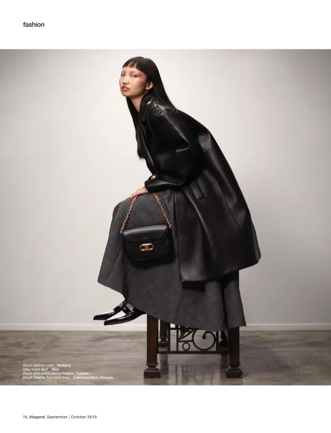  ??  ?? Black leather coat _ Versace
Grey wool skirt _ Dior
Black and white penny loafers _ Loewe Black Chaîne Triomphe bag _ Celine by Hedi Slimane