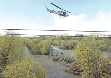  ?? STAN LIM/ THE ASSOCIATED PRESS ?? A women is hoisted out with the help of a San Bernardino County Sheriff’s helicopter on Tuesday, in the Santa Ana River and near the borders of Rialto, Colton, and Riverside, Calif.