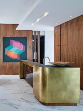  ??  ?? The pared back kitchen featuring marble, a patinated brass counter and granite work surface also has an abstract painting by Andrzej Urbanski.