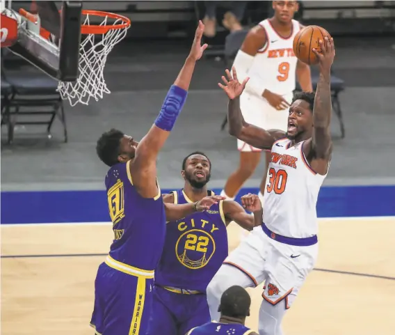  ?? Wendell Cruz / Associated Press ?? New York’s Julius Randle shoots against the Warriors' Kevon Looney (5) and Andrew Wiggins. Randle had 25 points, 10 rebounds and seven assists.