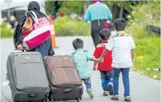  ?? GEOFF ROBINS/GETTY IMAGES ?? Asylum seekers walk along Roxham Road near Champlain, N.Y., on Aug.6, making their way towards the Canada/U.S. border.