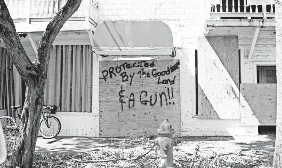  ?? PHOTOS BY TREVOR HUGHES, USA TODAY ?? A sign on a Duval Street store in Key West warns looters to stay away; otherwise, they might face divine retributio­n or an angry Second Amendment supporter.