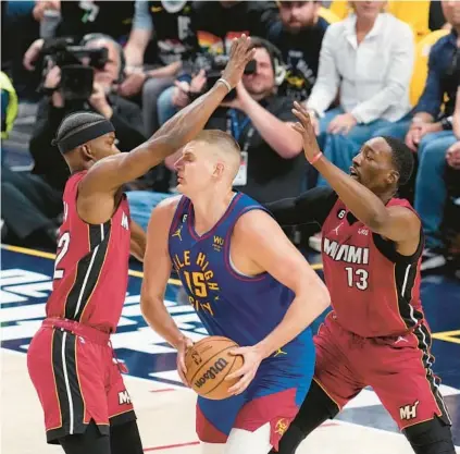  ?? DAVID ZALUBOWSKI/AP ?? Jimmy Butler, left, and Bam Adebayo, right, defend against Nikola Jokic on Thursday in the first half of NBA Finals Game 1 in Denver.