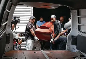  ?? Photos by Elmer Martinez / Associated Press ?? On Monday, men place the coffin of their family member Dionisio Heriberto Solis, one of the prisoners who died the previous day in a riot inside El Porvenir prison, into a hearse in Tegucigalp­a, Honduras.