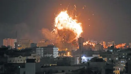  ??  ?? Una bola de fuego se observa sobre el edificio de la televisión dirigida por Hamas al-Aqsa TV en la ciudad de Gaza, tras el impacto de misiles israelíes.