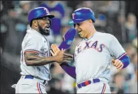  ?? The Associated Press ?? Lindsey Wasson
Adolis Garcia, left, greets Nathaniel Lowe after they scored on Jonah Heim’s single in Texas’ 6-1 win over the host Mariners on Saturday.