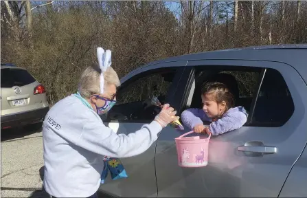  ?? BILL DEBUS - THE NEWS-HERALD ?? Leslie Mizen, left, a member of Hope Ridge United Methodist Church, distribute­s a treat bag to a child whose family participat­ed in the Concord Township Bunny Trail Easter Egg Hunt on March 27.