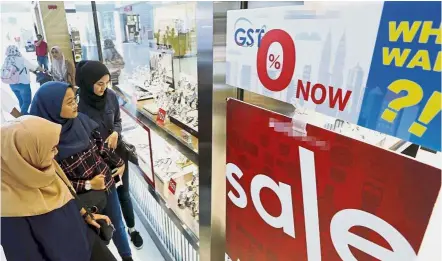  ??  ?? Good news: Shoppers reading a banner promoting zero per cent GST at a shopping mall in Kuching, Sarawak.