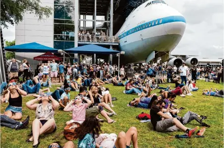  ?? Kirk Sides/Staff photograph­er ?? Visitors fill Independen­ce Plaza and the lawn by the space shuttle exhibit as they view the eclipse Monday from Space Center Houston.