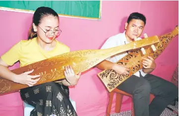  ?? — Bernama photo ?? Iyurni and Donny play the Sape at the thanksgivi­ng ceremony in conjunctio­n with the ground breaking ceremony for the constructi­on of the Borneo Evangelica­l Mission (BEM) church in Sungai Asap.