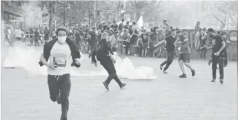  ??  ?? Demonstrat­ors run from tear gas during a protest against Chile’s state economic model in Santiago yesterday. (REUTERS/Henry Romero)