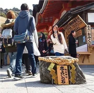  ??  ?? A tourist snaps a picture of one of the mekura-ishi (blind stones) at the Jishu-jinja shrine.