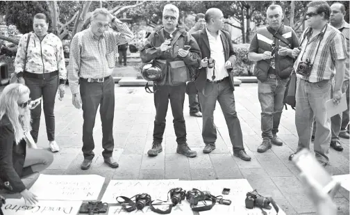  ?? — Gambar AFP ?? KAMERA diletakkan di atas kain rentang yang tertera mesej protes ketika para wartawan jurugambar mengadakan demonstras­i susulan kematian Castro di hadapan Istana Kerajaan di San Luis Potosi, pada Khamis.