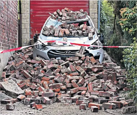  ?? ?? A car is crushed by hundreds of bricks in Huddersfie­ld as Storm Malik brings winds of up to 147 mph to the Midlands, the North, Northern Ireland and Scotland